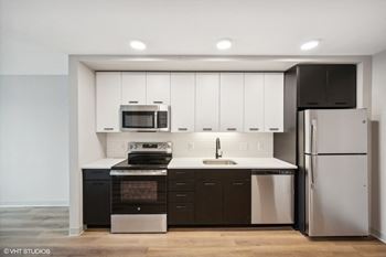 a kitchen with white cabinets and black appliances and a stainless steel refrigerator